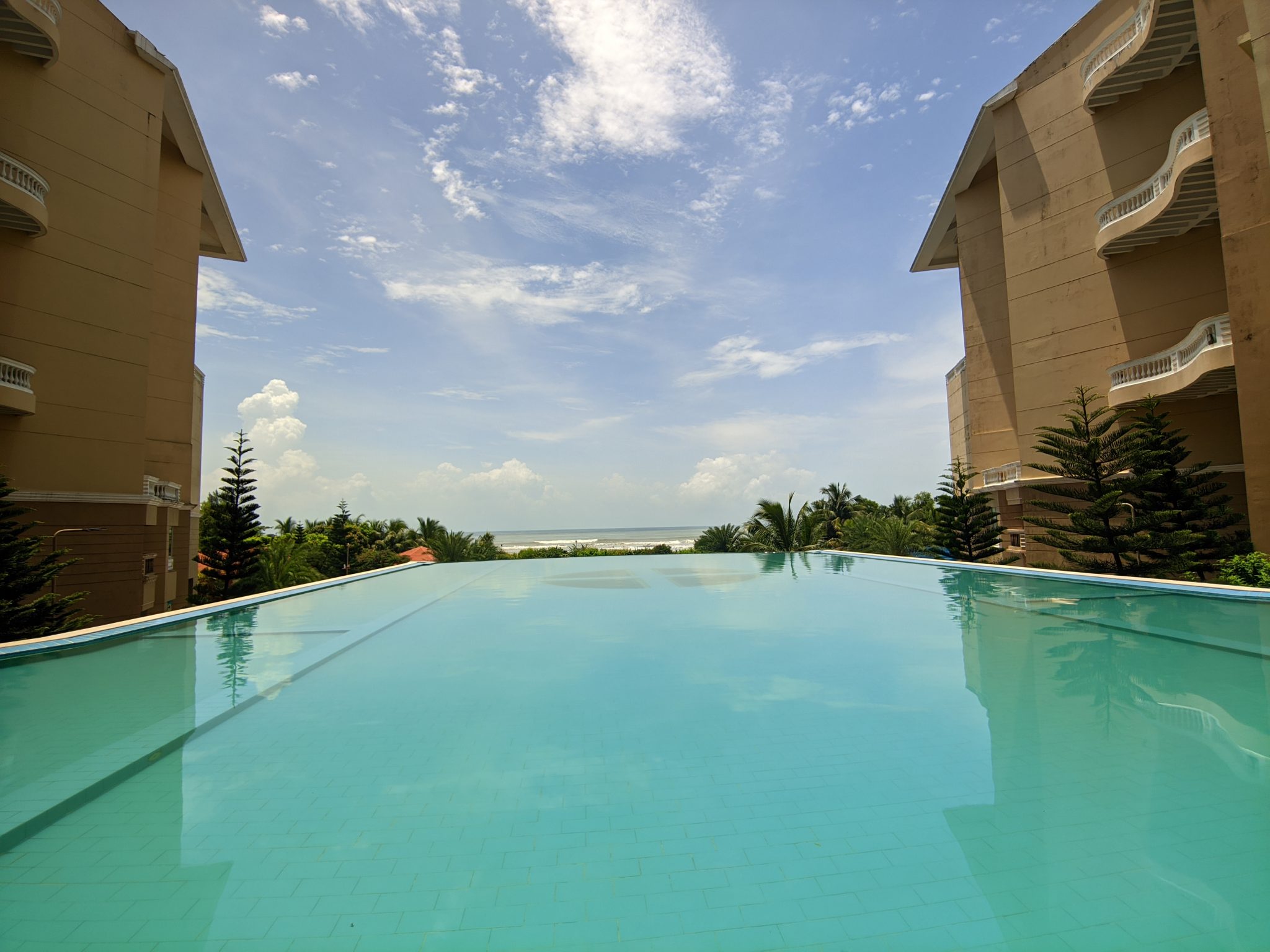 Otel Havuzundan Eşsiz Deniz Manzarası ve Bulutlu Mavi Gökyüzü Altında Tatil Havası