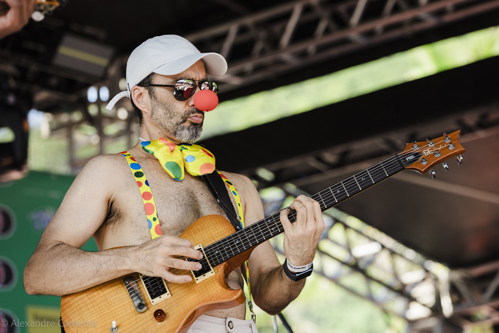 Palyaço burunlu renkli aksesuarlarıyla sahne alan müzisyen elektro gitar çalıyor