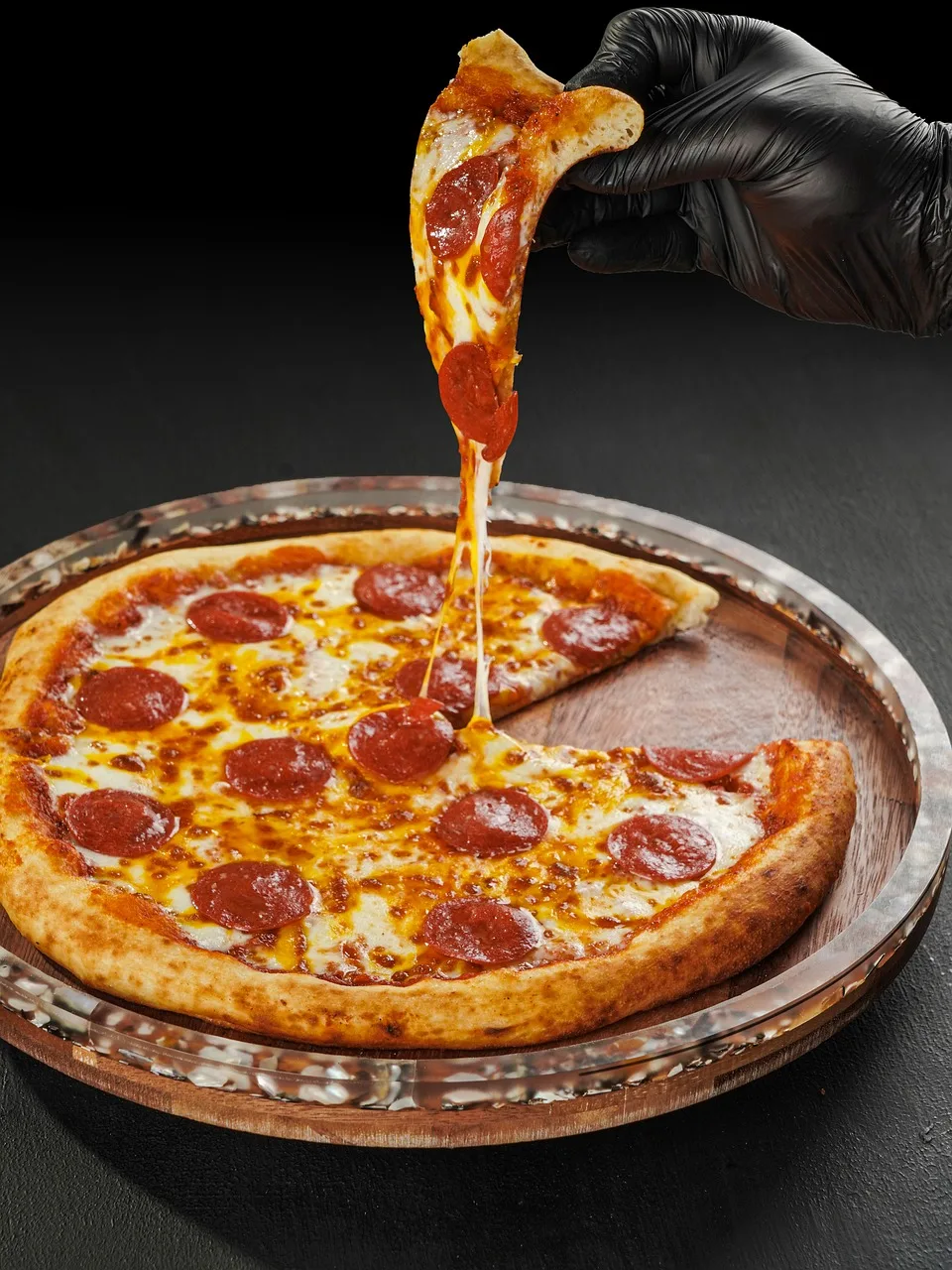 Pepperoni pizzası dilimlenmiş ahşap tabağın üzerinde