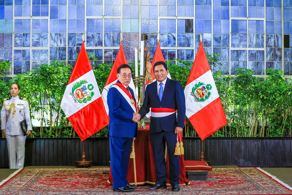 Peru bayrakları önünde resmi törende el sıkışan devlet erkanı ve askeri personel
