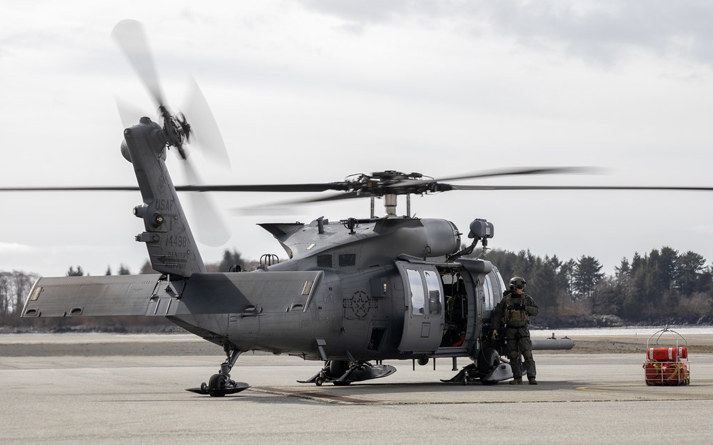 Pistte pervaneleri dönen gri askeri helikopter ve kontrol eden personel