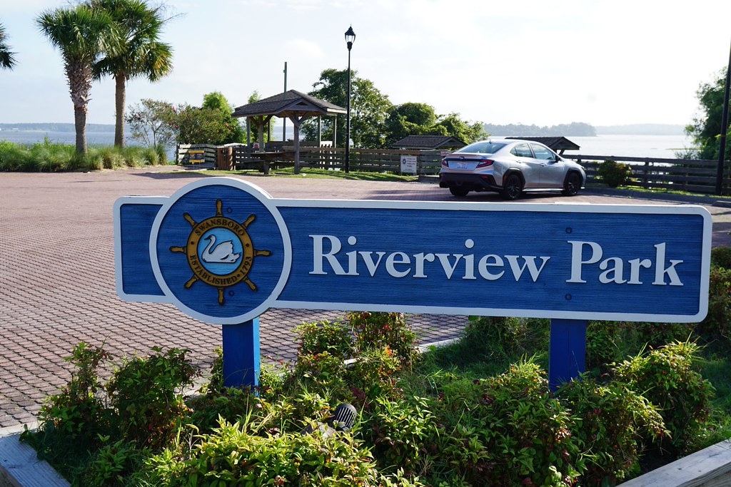 riverview park tabelası önünde nehir kenarında huzurlu park manzarası