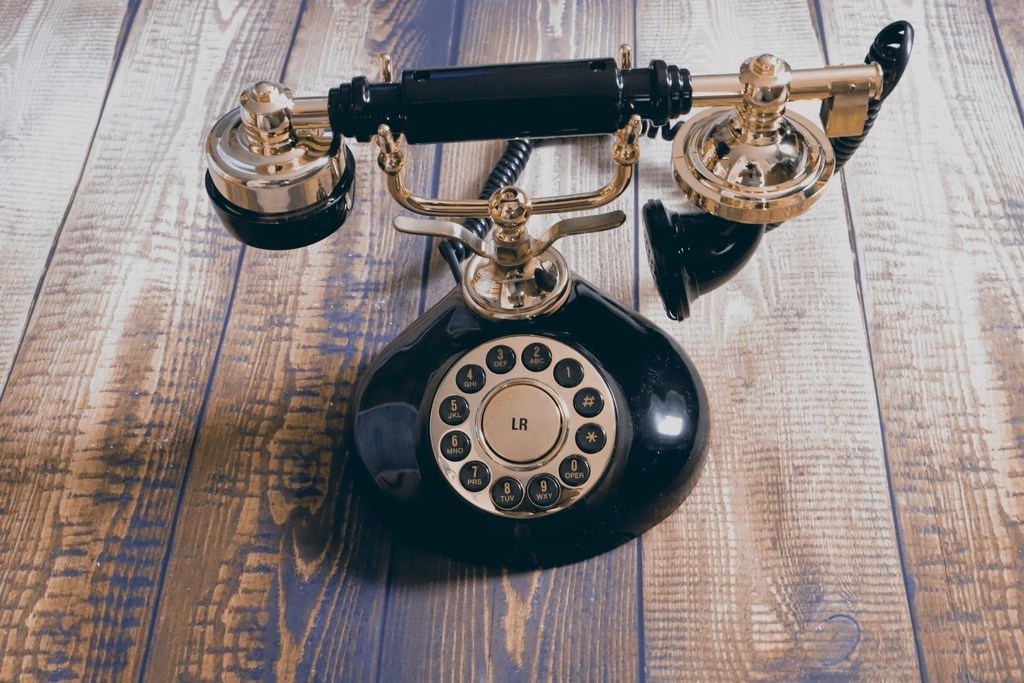 rustik ahşap zemin üzerinde altın kaplamalı siyah antika çevirmeli telefon
