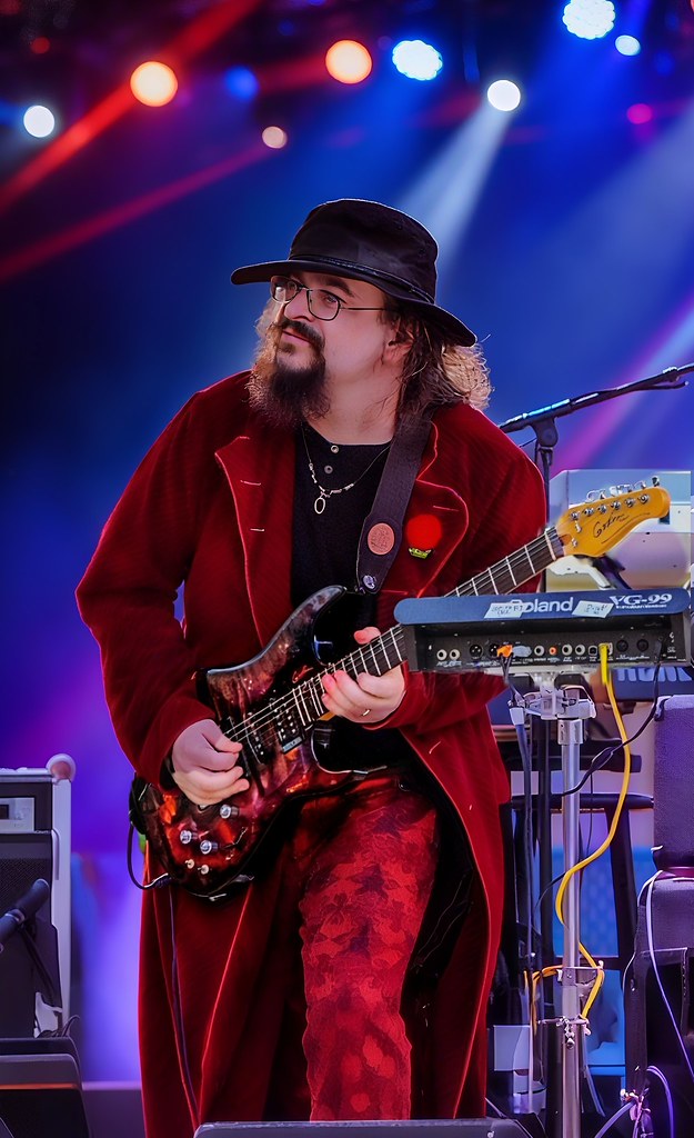 Sahne Işıkları Altında Kırmızı Kadifeli Gitarist ve Canlı Müzik Performansı