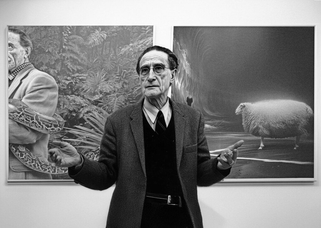 Sanat galerisinde eserleriyle poz veren yaşlı sanatçının siyah beyaz portresi