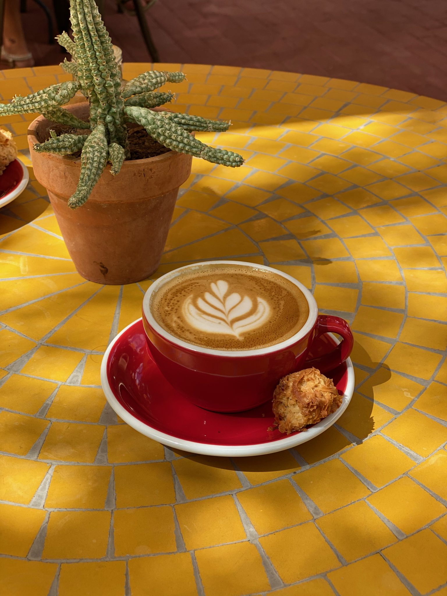 Sarı Mozaik Masada Kırmızı Fincanda Latte Artlı Kahve ve Kaktüs Detayı