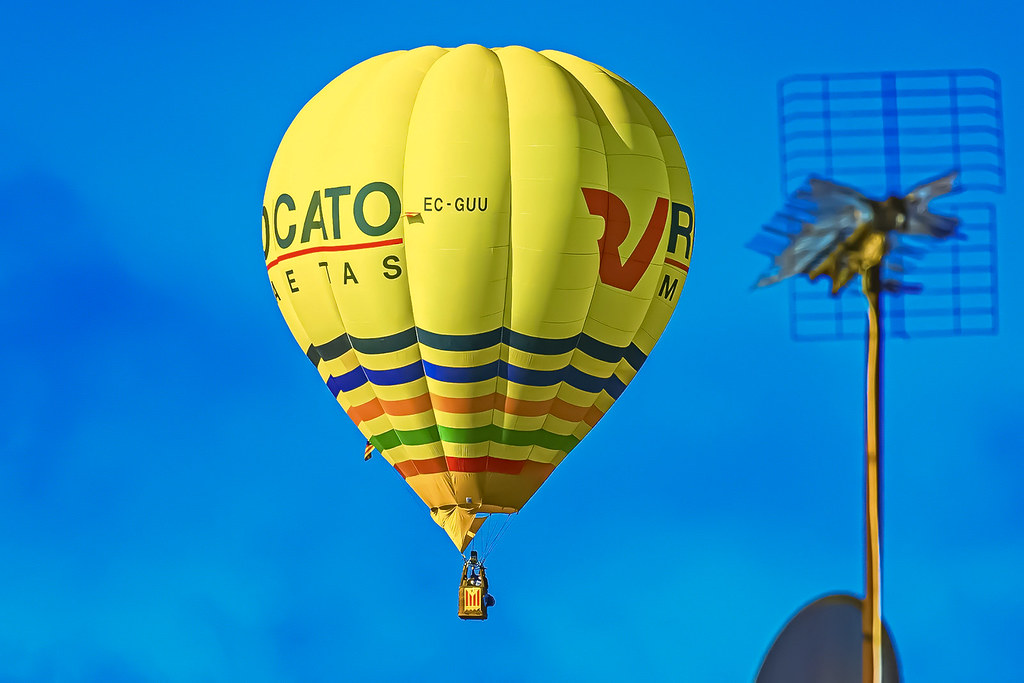 Sarı Sıcak Hava Balonunun Rengarenk Çizgileriyle Mavi Gökyüzünde Görkemli Uçuşu