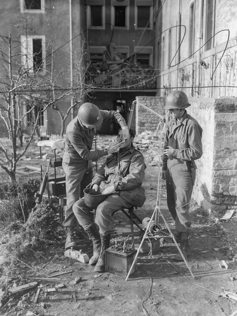 Savaşta Kuaför: Harabe Bir Binanın Önünde Askeri Tıraş Anı, 1940'lar Savaşta Kuaför: Harabe Bir Binanın Önünde Askeri Tıraş Anı, 1940'lar