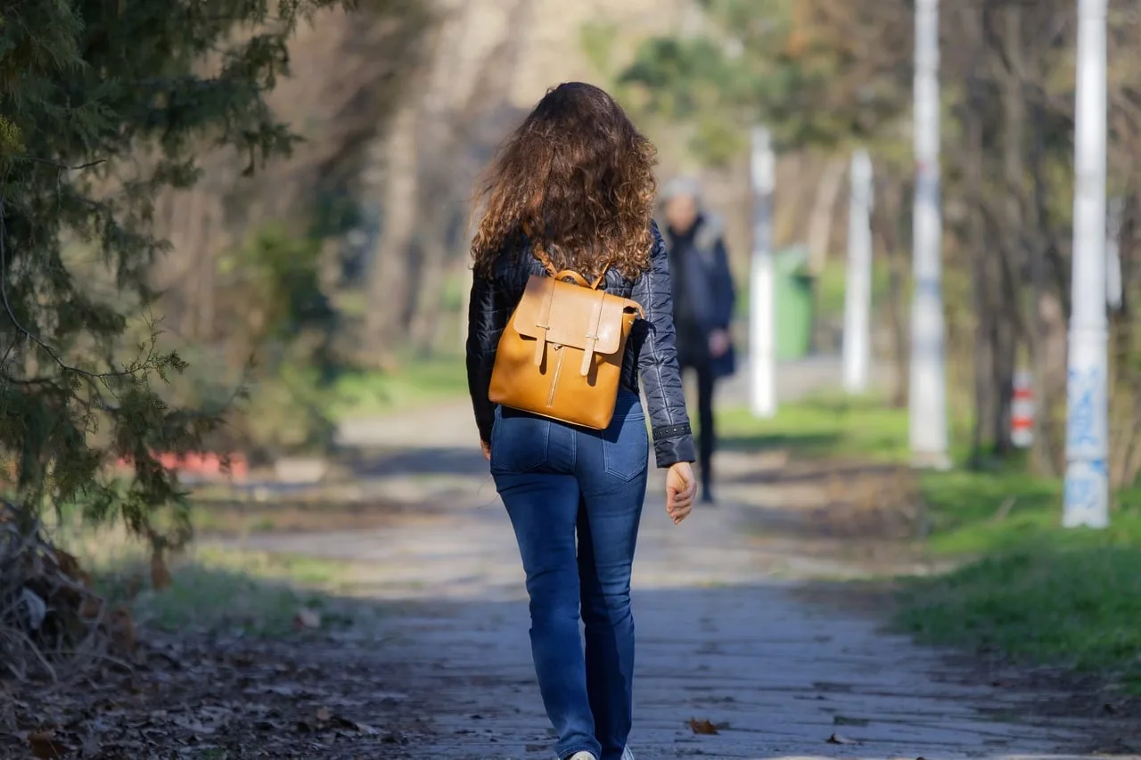 Sırt çantalı genç kız parkta yürüyüş yapıyor Sırt çantalı genç kız parkta yürüyüş yapıyor