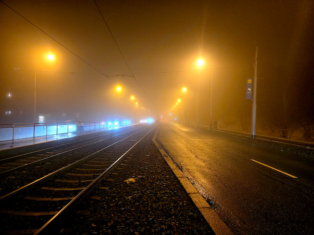 Sisli Gecede Tramvay Rayları ve Sarı Sokak Lambalarıyla Gizemli Şehir Manzarası