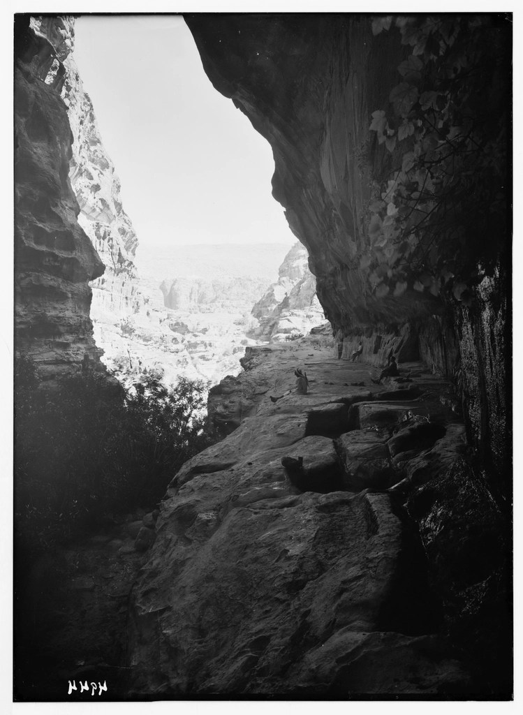 Siyah beyaz arşiv fotoğrafta gizemli kanyon içindeki tarihi kaya yolu ve uzak figürler