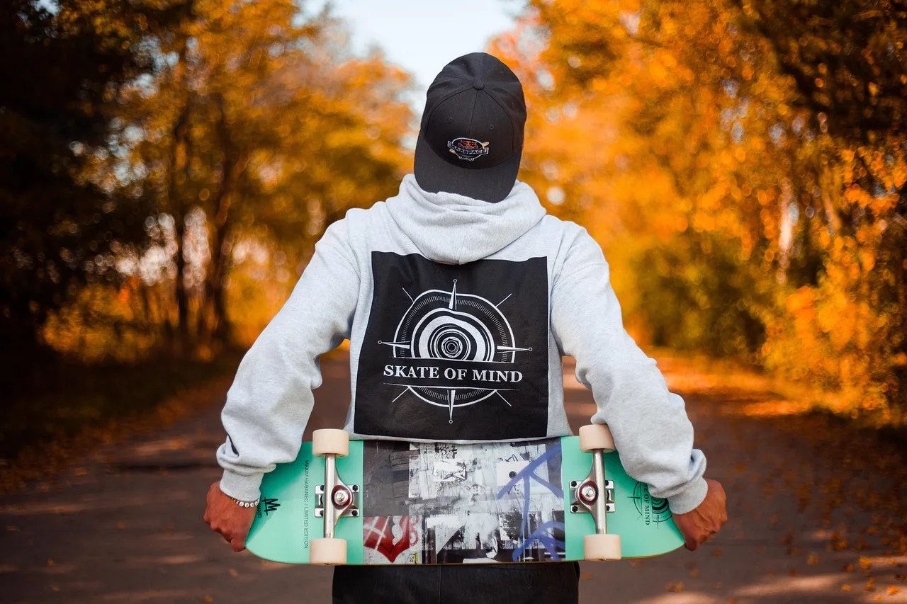 Skateboardlu adam sonbahar doğa yürüyüşü - renkli yapraklar