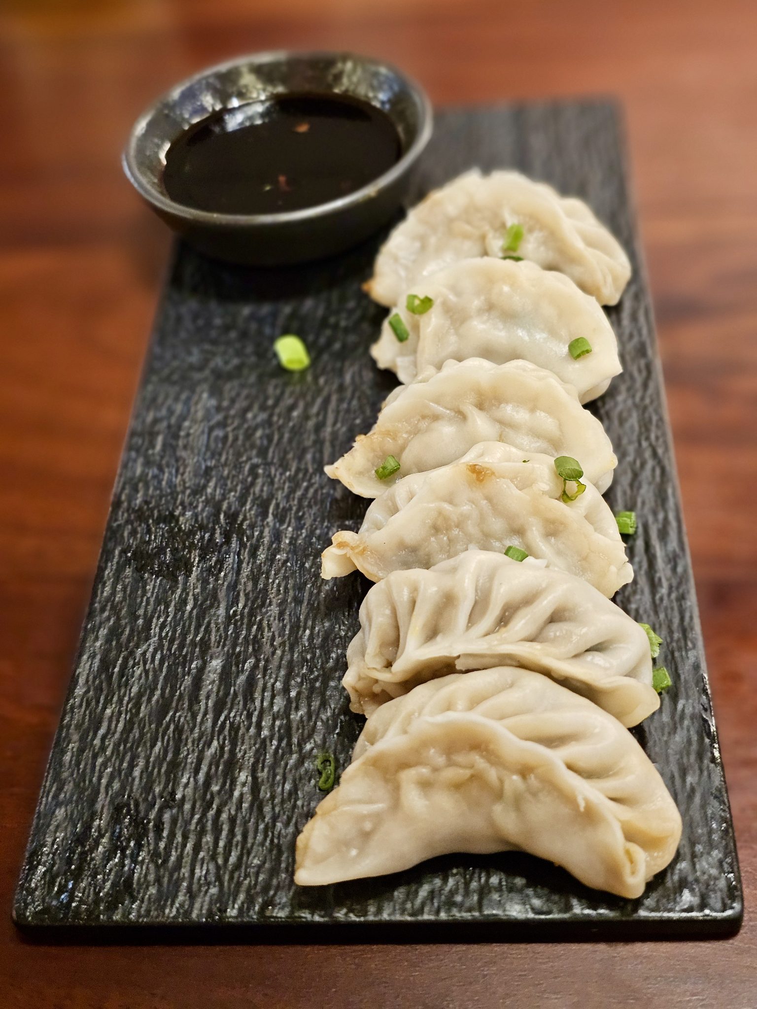 Soya sosu eşliğinde sunulan taze gyoza mantıları siyah taş sunum tahtasında
