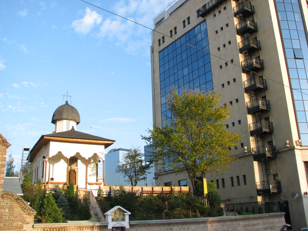 Tarihi kubbeli kilise ile modern cam gökdelenin bir arada olduğu şehir manzarası