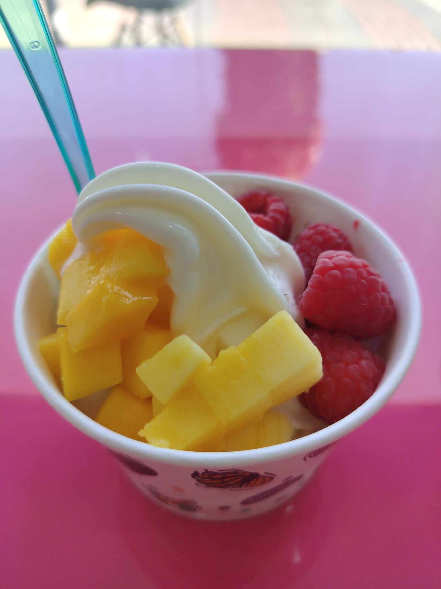 Taze mango ve ahududu parçalarıyla süslenmiş kremalı dondurma kasesi