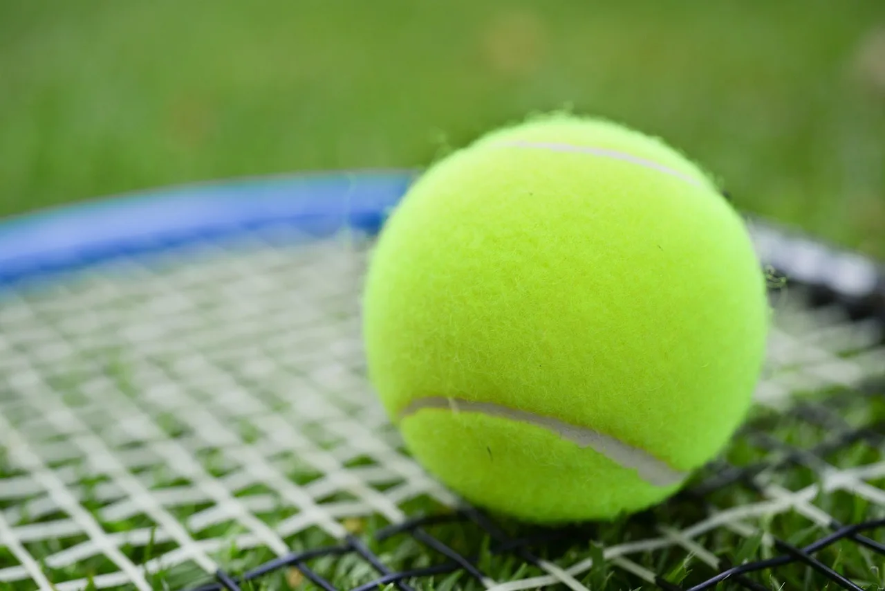 Tenis kortunda sarı top ve raket