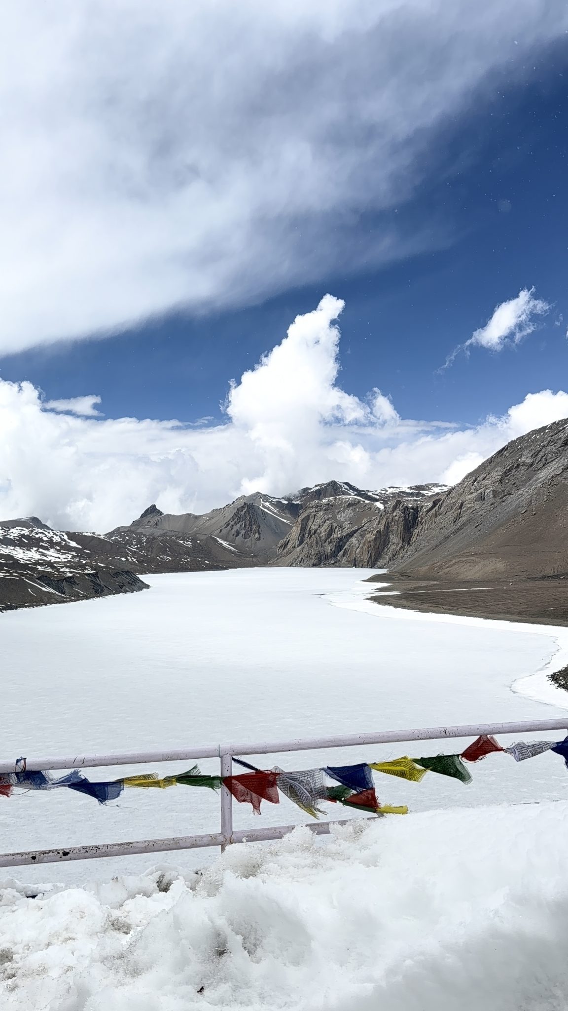 Tibet'te Renkli Dua Bayrakları ve Buzla Kaplı Yüksek Dağ Gölü Manzarası