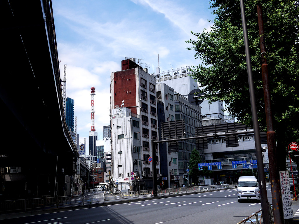 Tokyo sokaklarında güneşli günde modern binalar ve yeşil ağaçlı kent manzarası