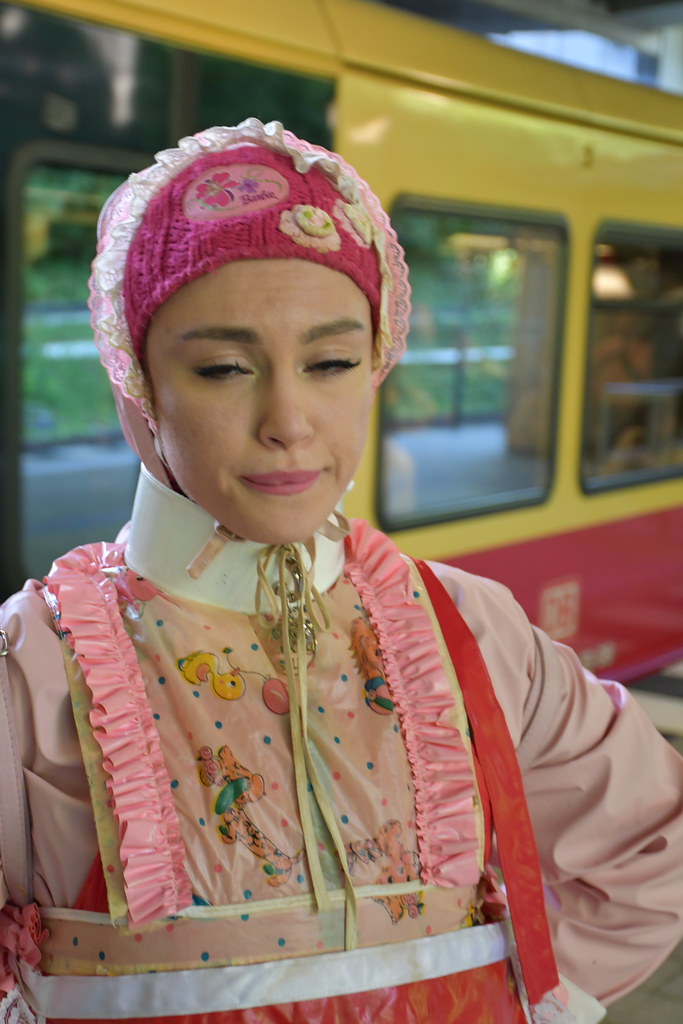 Tramvay önünde pembe örgü şapkalı desenli fırfırlı kıyafetli kadın portresi