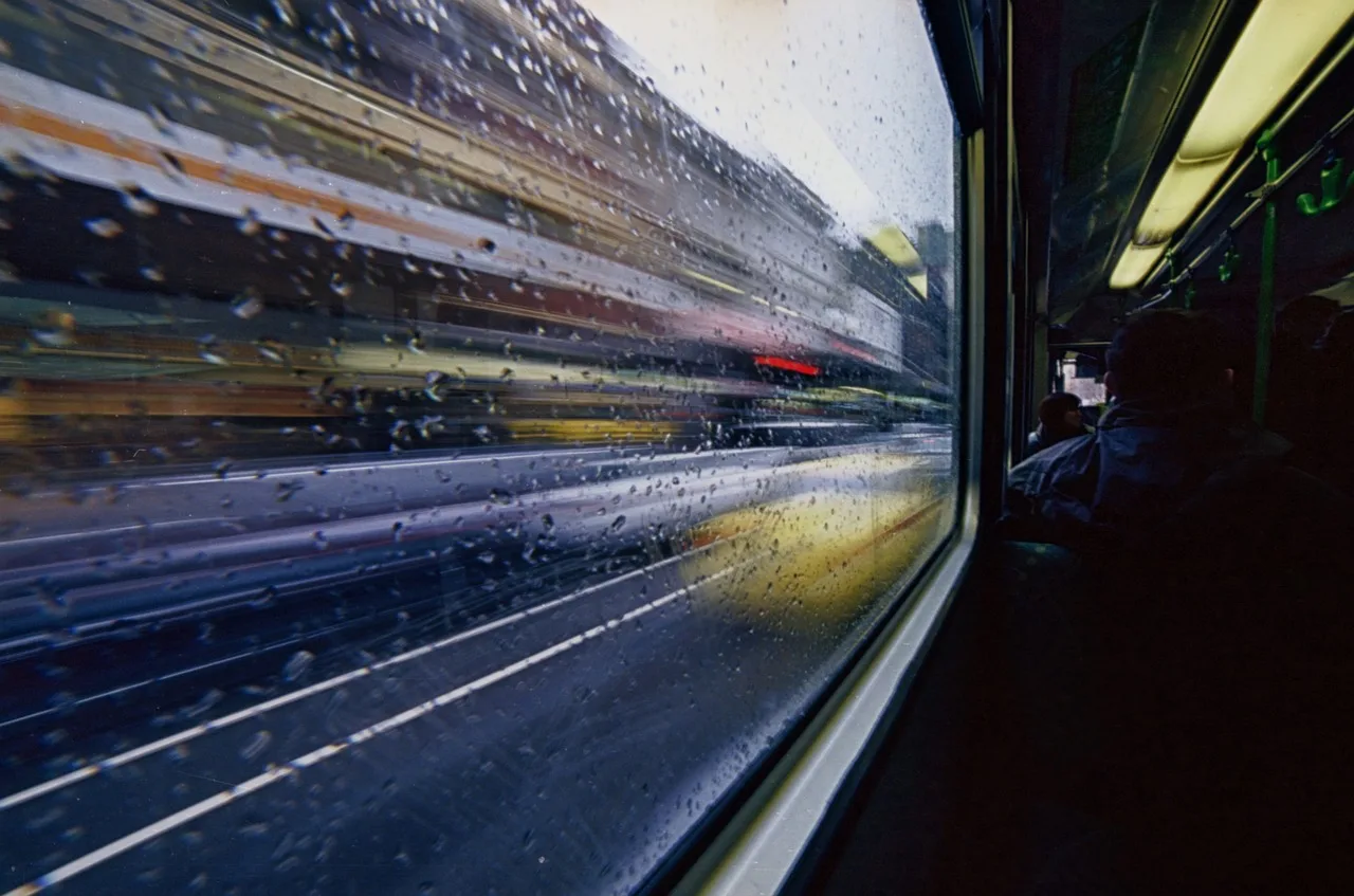 Tramvay ve otobüs yağmur damlalarıyla cam pencerede