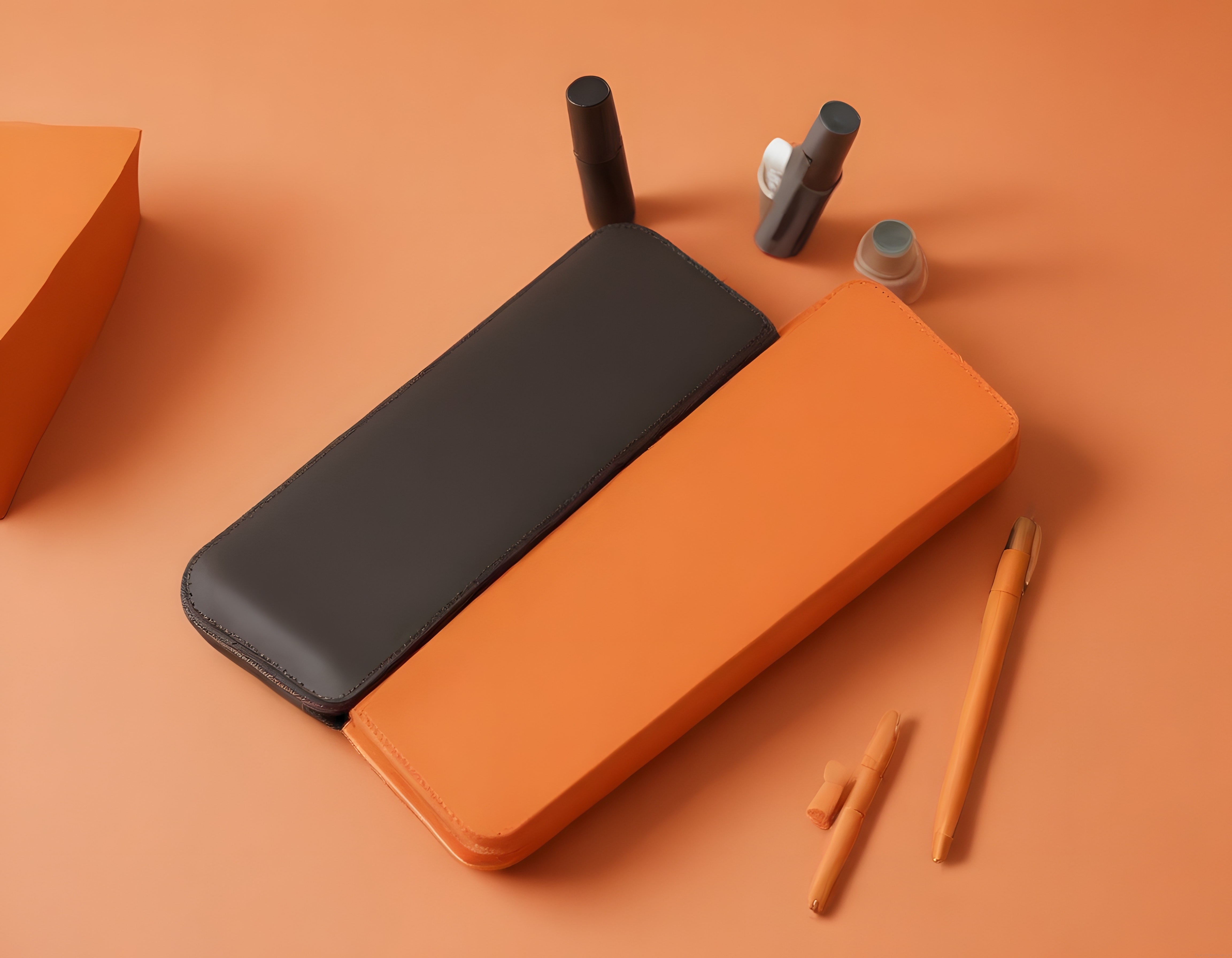 Turuncu ve siyah deri kalem kutusu ile minimalist ürün kompozisyonu
