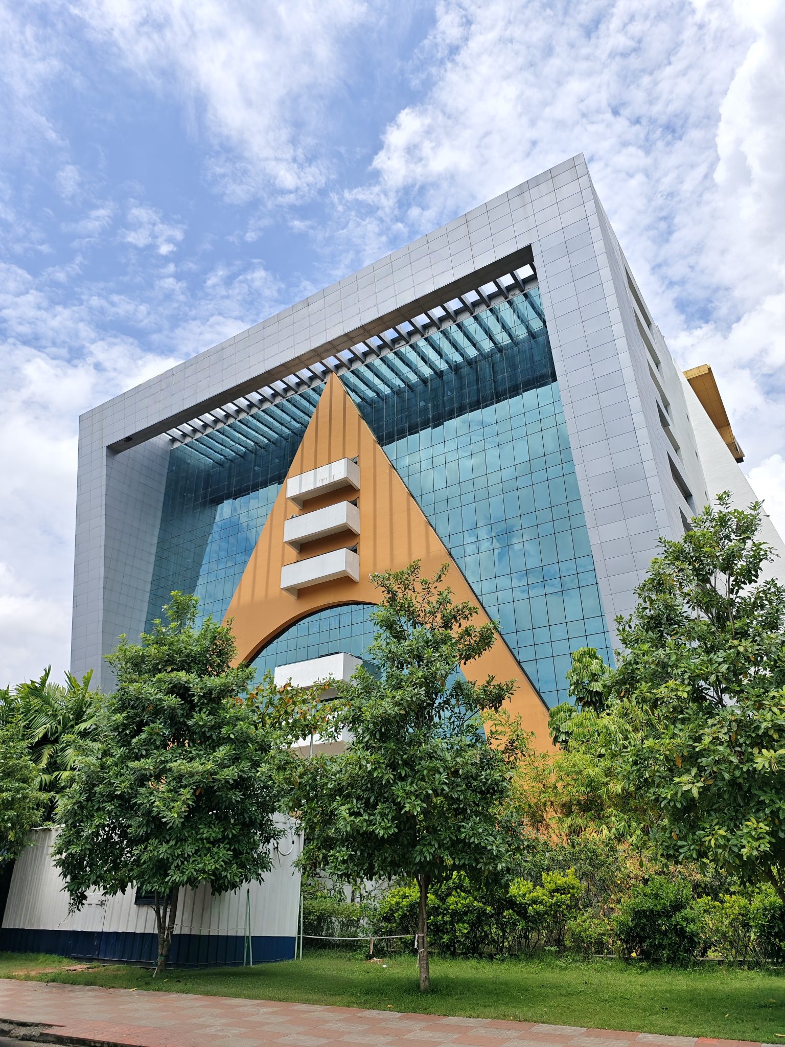 Üçgen Detaylı Çağdaş Ofis Binası ve Bulutlu Mavi Gökyüzü Manzarası
