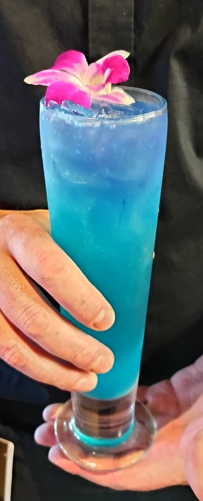 Uzun Bardakta Tropikal Mavi Kokteyl ve Pembe Orkide ile Göz Alıcı İçecek Sunumu