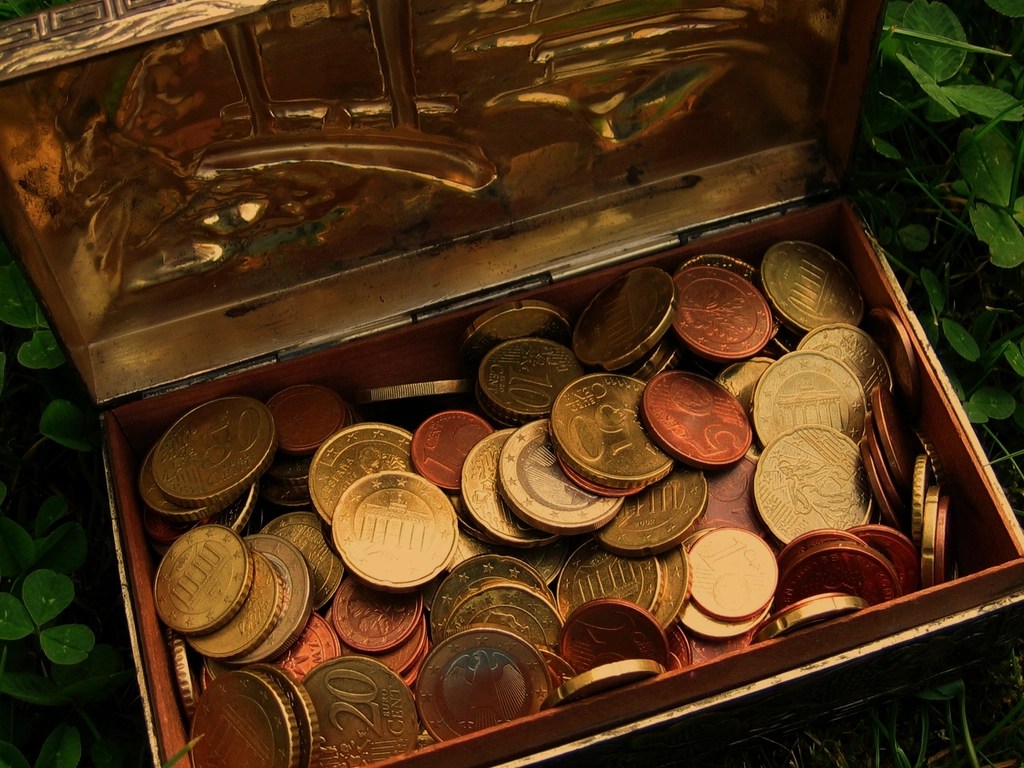 Yerde açık eski hazine sandığında birikmiş altın rengi bozuk paralar ve euro