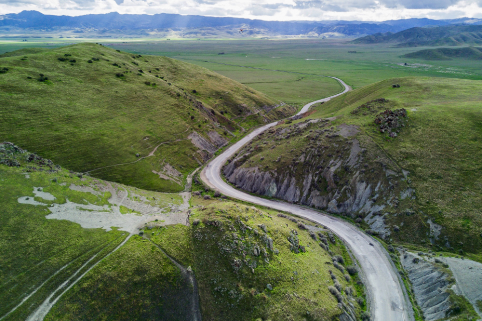 Yeşil Tepeler Arasından Geçen Dolambaçlı Yol ve Uzakta Uzanan Dağlar